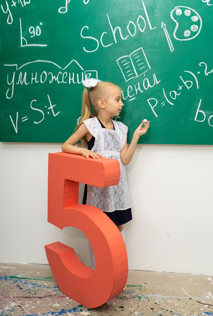 Девочка пишет мелом по школьной доске