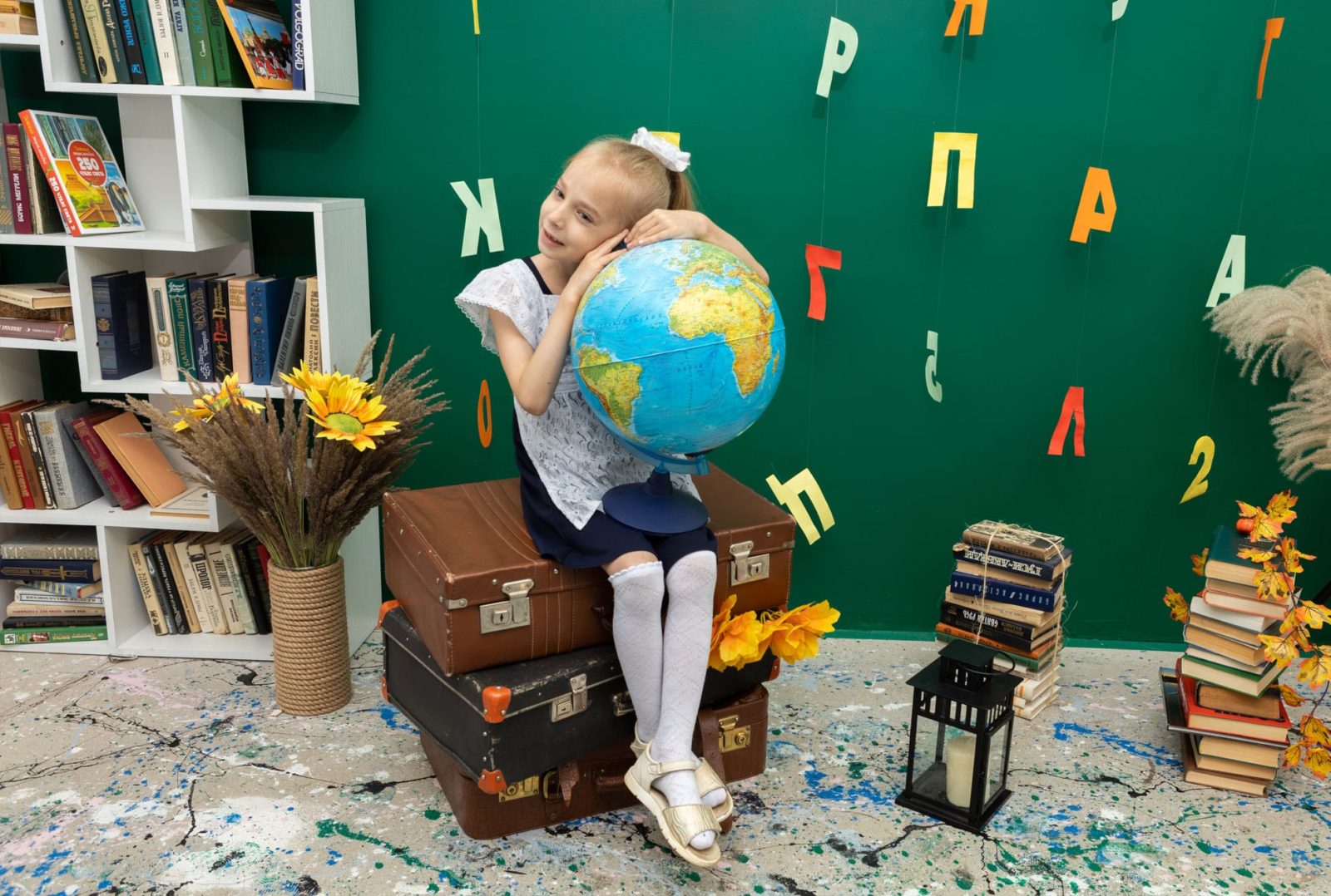 Девочка в форме с глобусом в руках на фоне полки с книгами
