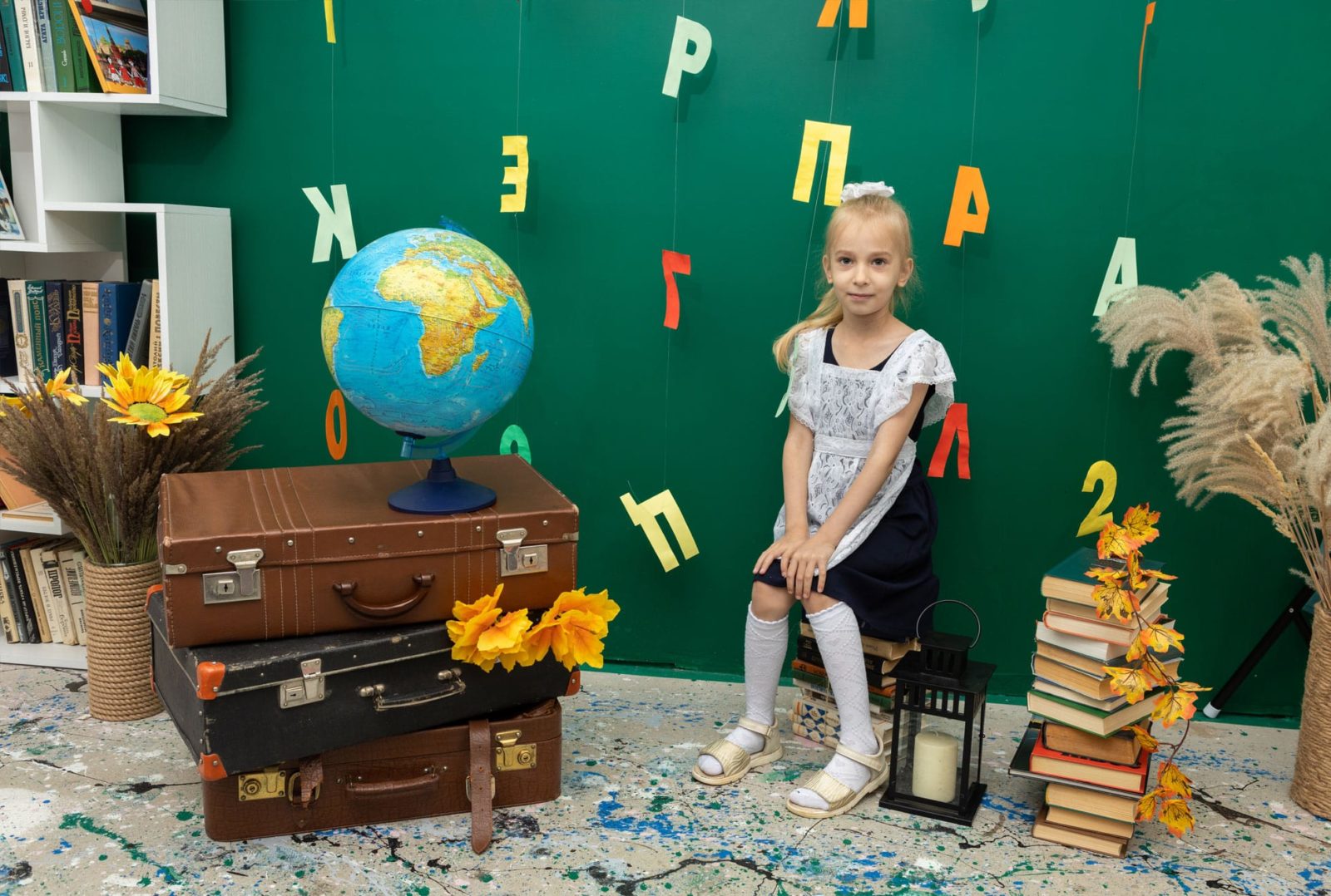 Девочка в школьной форме сидит на стопке книг