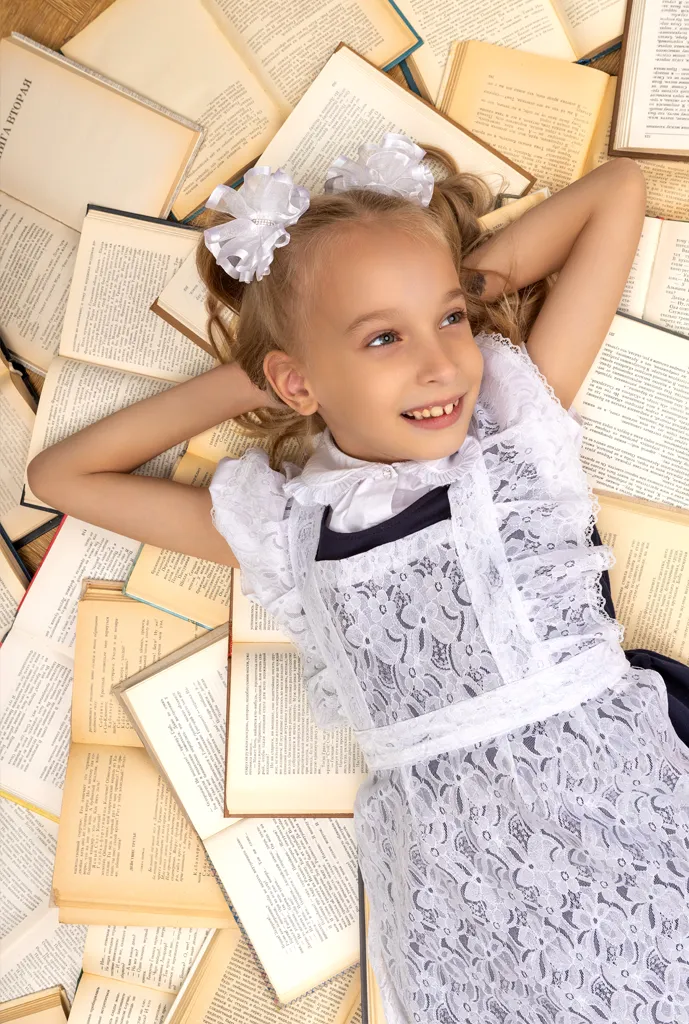 Девочка в школьной форме лежит на открытых книгах