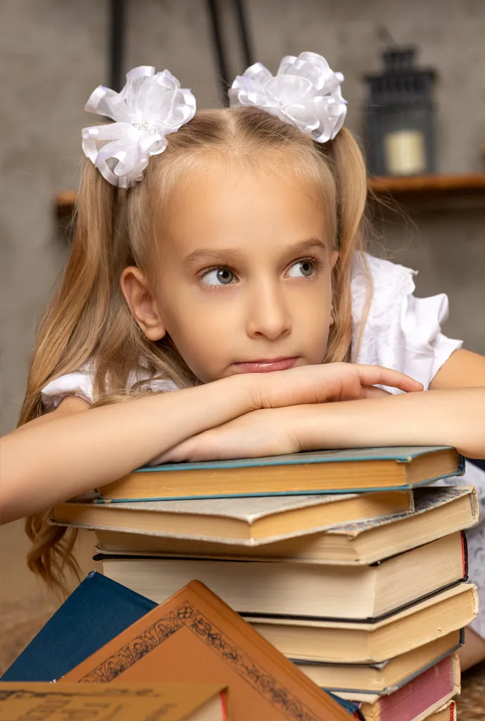 Задумчивая девочка оперлась на стопку книг