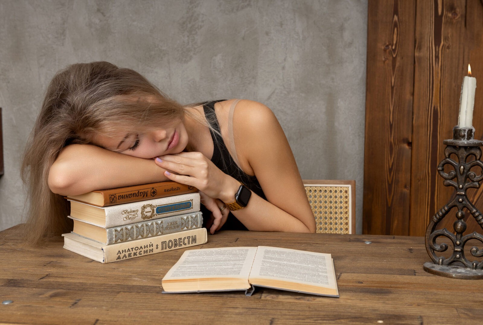 Девушка за столом спит на книгах
