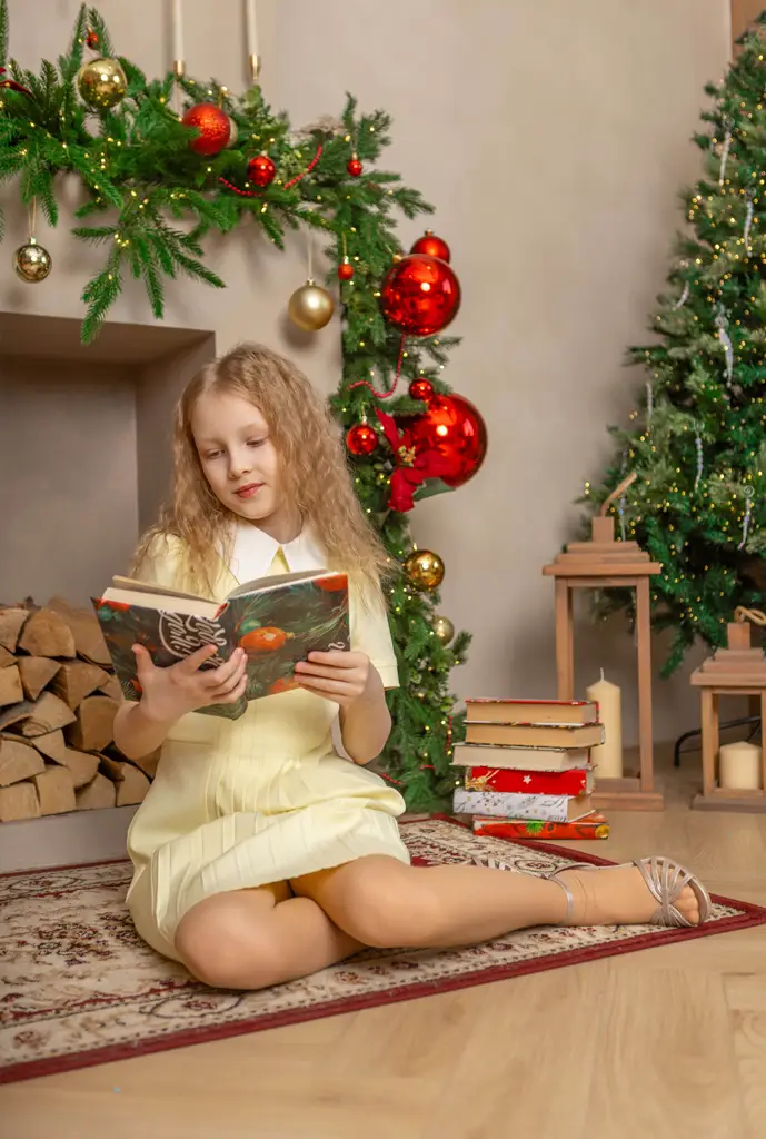 Девочка читает книгу на фоне камина украшенного в новогоднем стиле